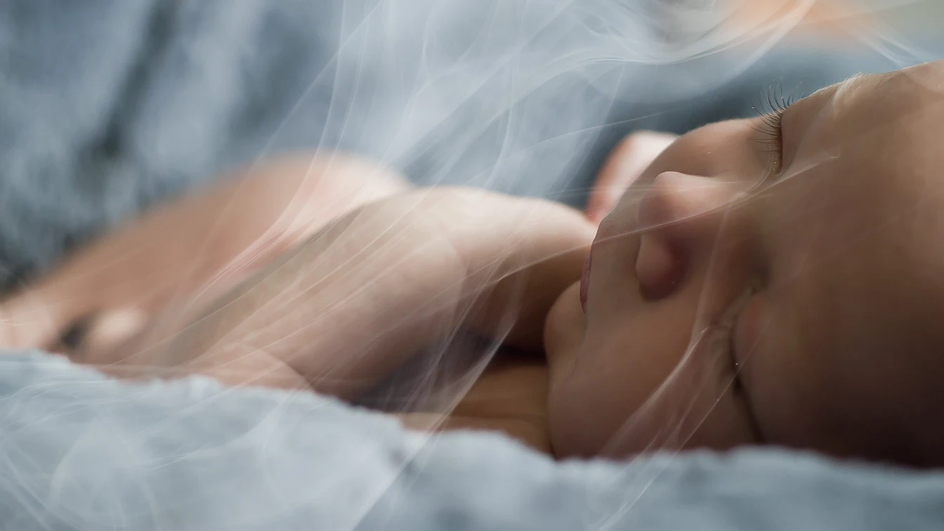 Un bebé respira el humo del tabaco Un bebé respira el humo del tabaco