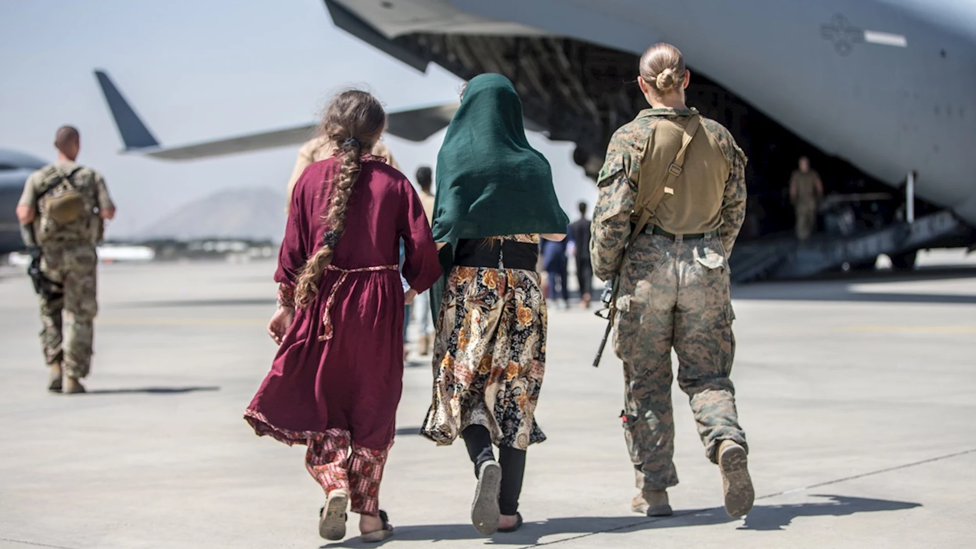 Una soldado acompaña a dos chicas afganas a un avión