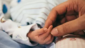 La mano de un bebé y la de una mujer.