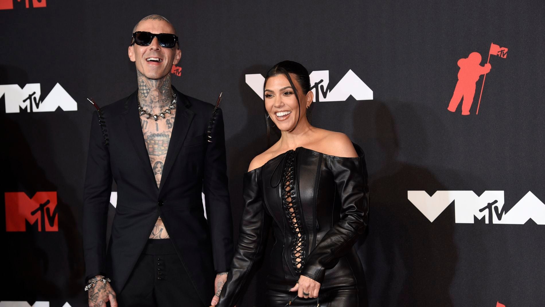 Kourtney Kardashian, con minivestido negro de cuero, junto a su pareja, Travis Barker