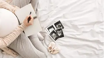 Mujer embarazada escribiendo en una libreta