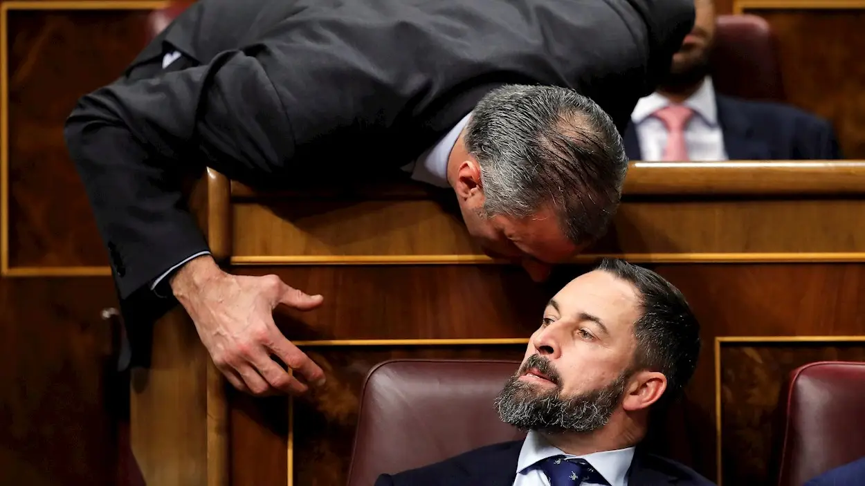 El presidente de Vox, Santiago Abascal, escucha a su compa&ntilde;ero de grupo, Javier Ortega Smith (i), en el Congreso de los Diputados en la primera jornada de la sesi&oacute;n de investidura de Pedro S&aacute;nchez como presidente del Gobierno