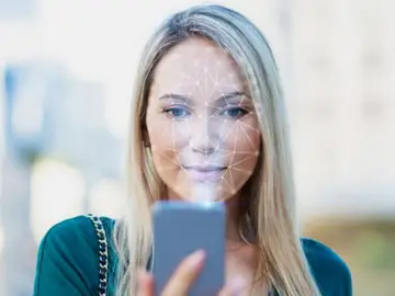 Foto de archivo de una mujer usando una app de reconocimiento facial