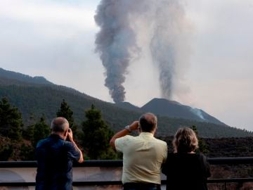 Un grupo de personas observan la columna de humo del volcán en La Palma
