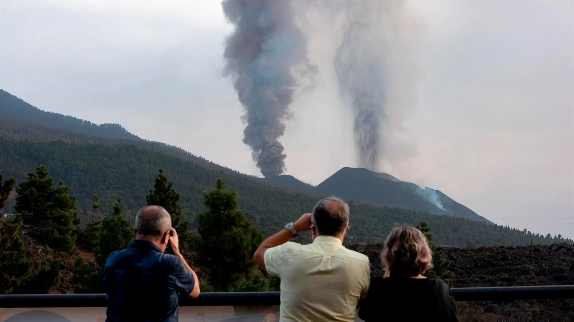 Un grupo de personas observan la columna de humo del volc&aacute;n en La Palma