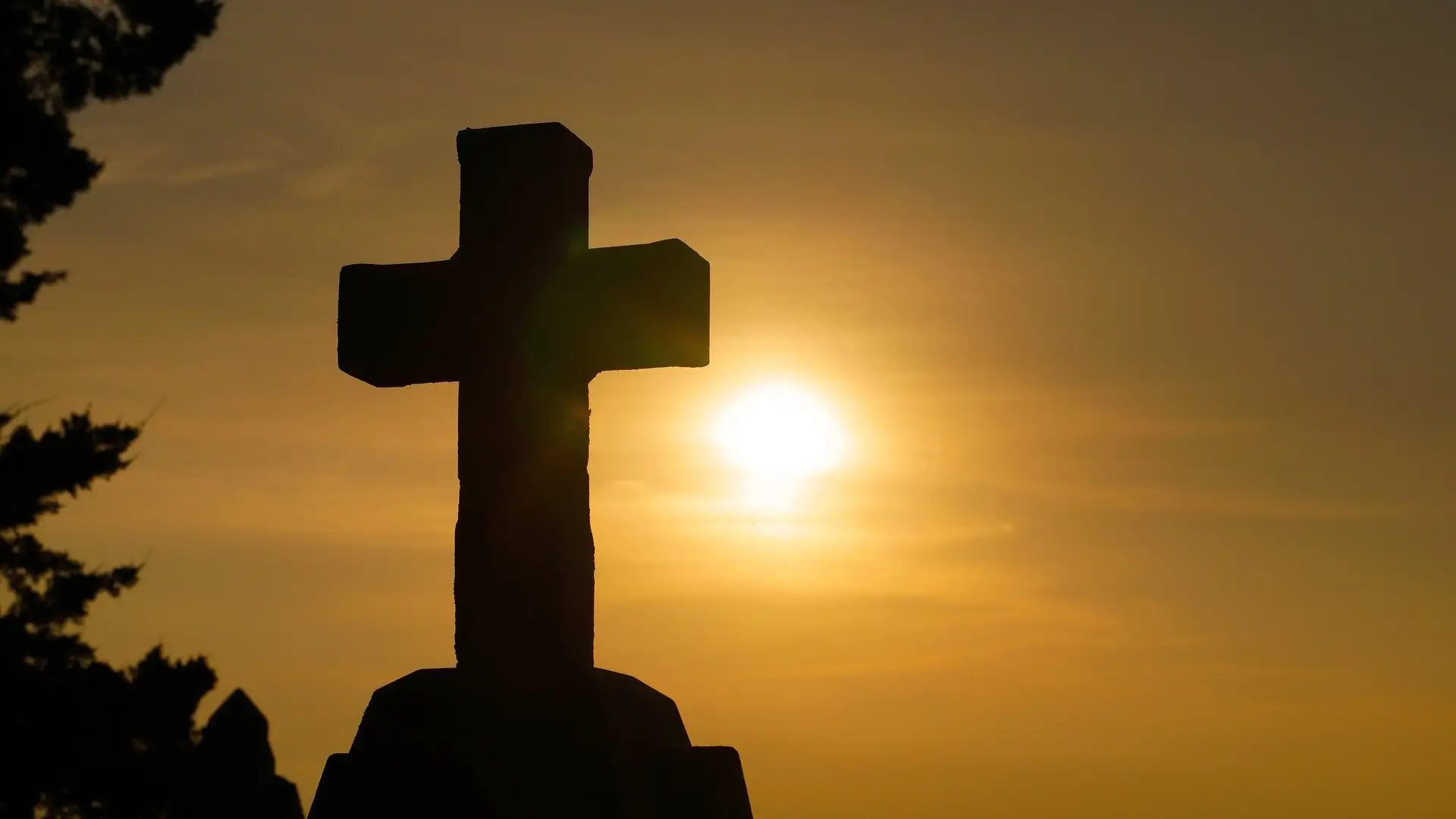 Imagen de una cruz con el sol de fondo