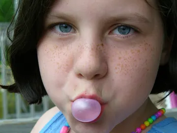 Una niña haciendo una pompa con un chicle Una niña haciendo una pompa con un chicle