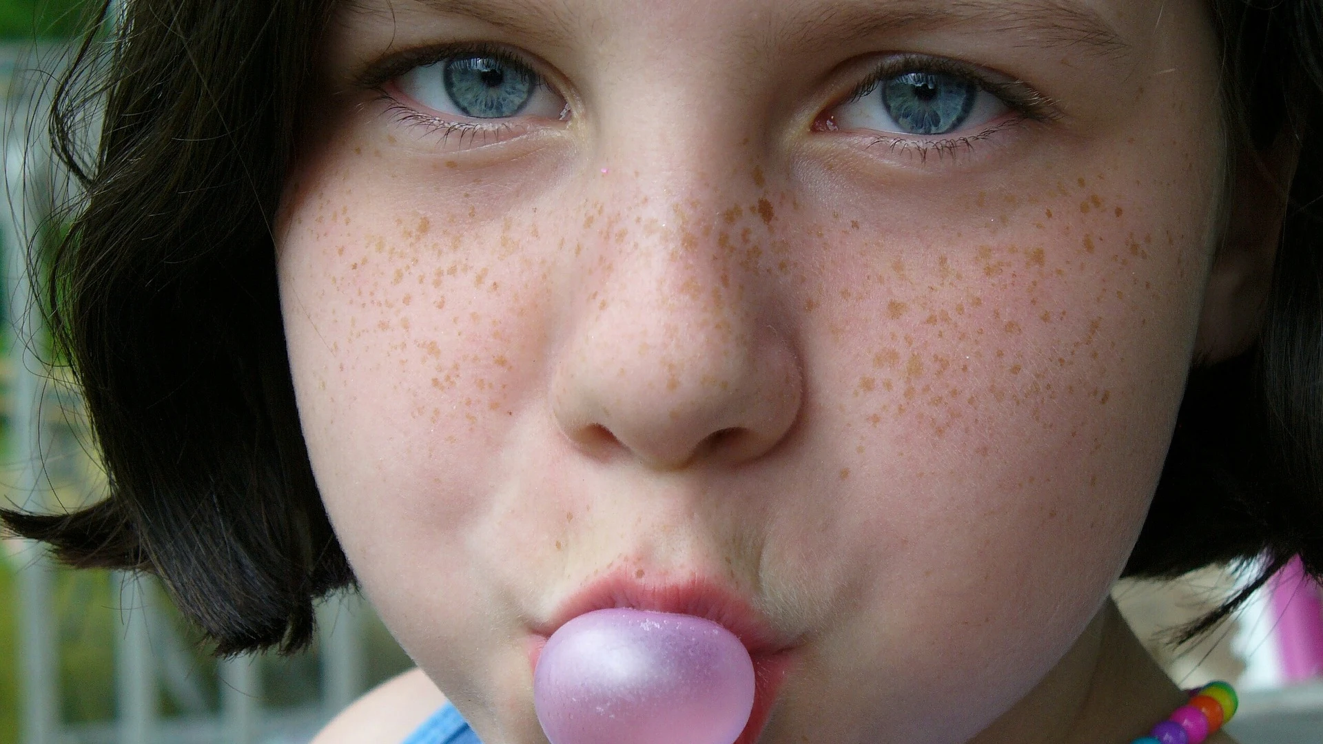 Una niña haciendo una pompa con un chicle Una niña haciendo una pompa con un chicle