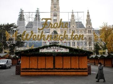Una mujer camina por un mercado navideño cerrado frente al ayuntamiento de Viena. 