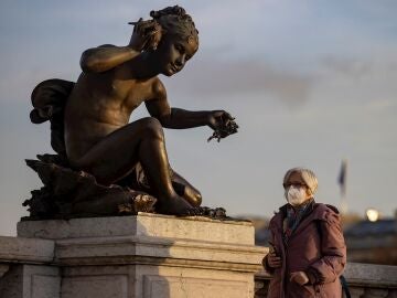 Una mujer con mascarilla protectora camina por el Puente Alexandre III este jueves en París