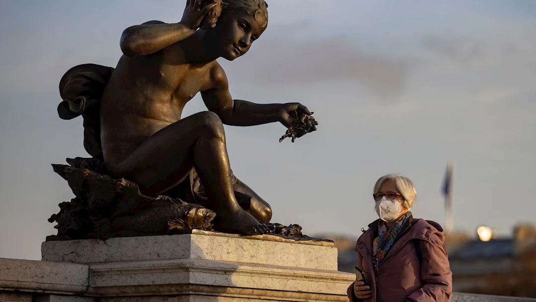 Una mujer con mascarilla protectora camina por el Puente Alexandre III este jueves en París Una mujer con mascarilla protectora camina por el Puente Alexandre III este jueves en París