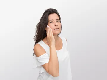Mujer tocándose la piel de la cara Mujer tocándose la piel de la cara