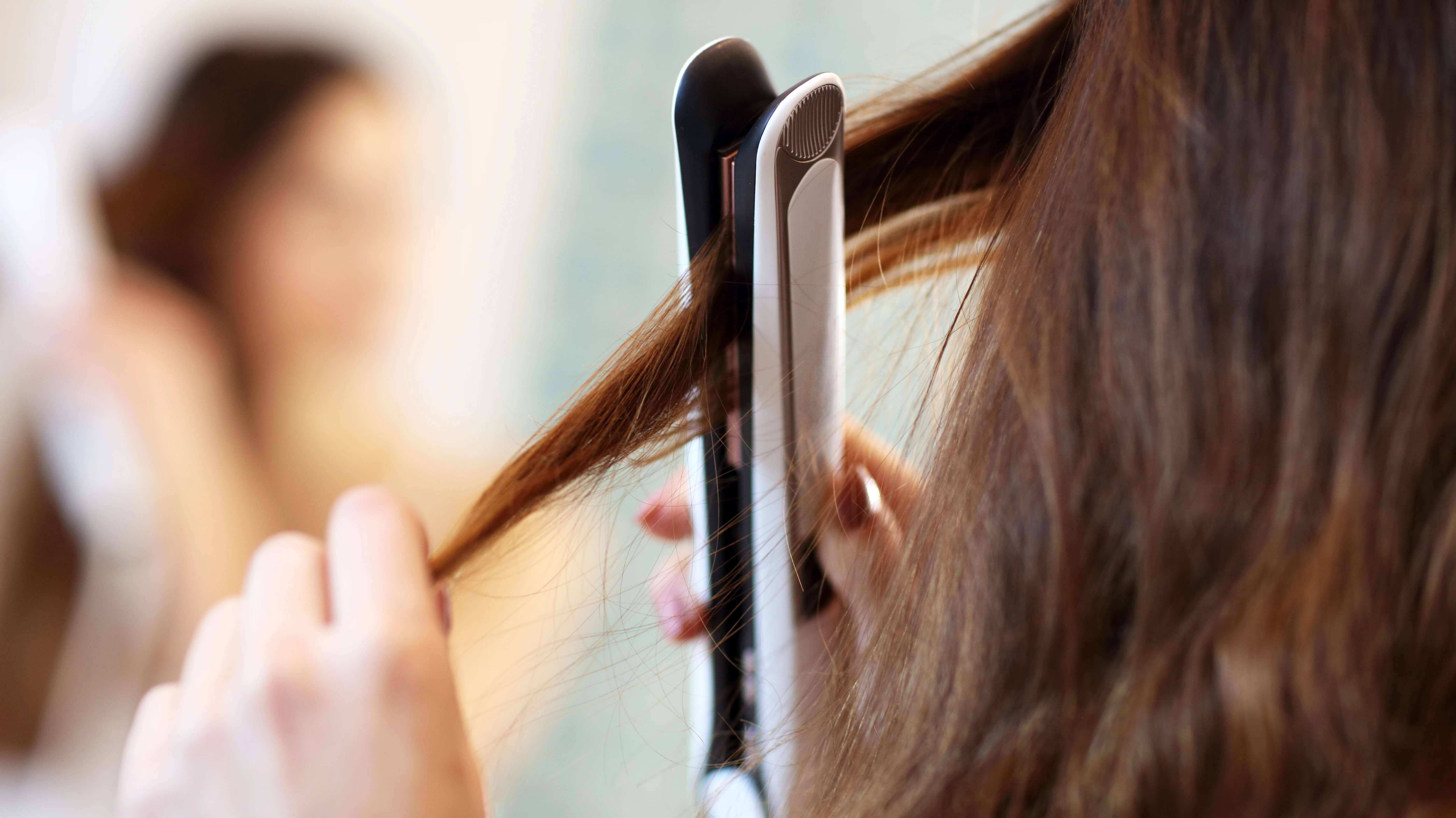 Chica planchándose el pelo. Chica planchándose el pelo.