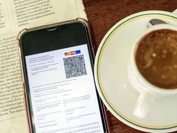Detalle de un certificado covid en un smartphone en una cafetería Detalle de un certificado covid en un smartphone en una cafetería