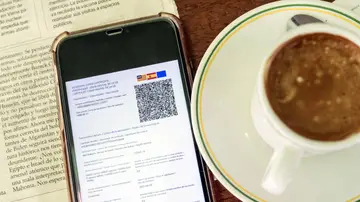 Detalle de un certificado covid en un smartphone en una cafetería