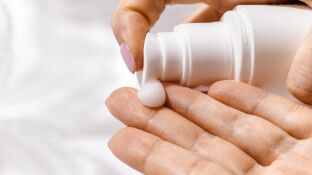 Una mujer echa crema en una mano