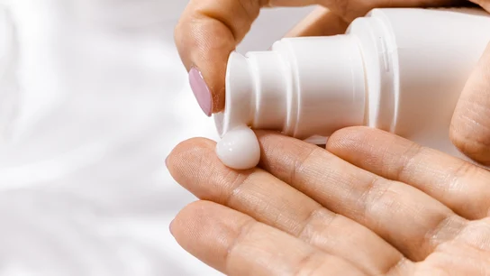 Una mujer echa crema en una mano Una mujer echa crema en una mano