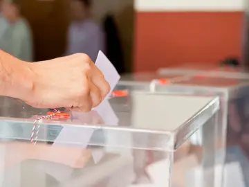 Foto de archivo de una persona introduciendo su voto en una urna electoral. Foto de archivo de una persona introduciendo su voto en una urna electoral.