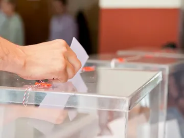 Foto de archivo de una persona introduciendo su voto en una urna electoral. Foto de archivo de una persona introduciendo su voto en una urna electoral.