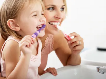 Madre e hija cepillándose los dientes Madre e hija cepillándose los dientes