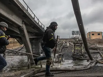 Militares ucranianos pasan junto a un puente destruido
