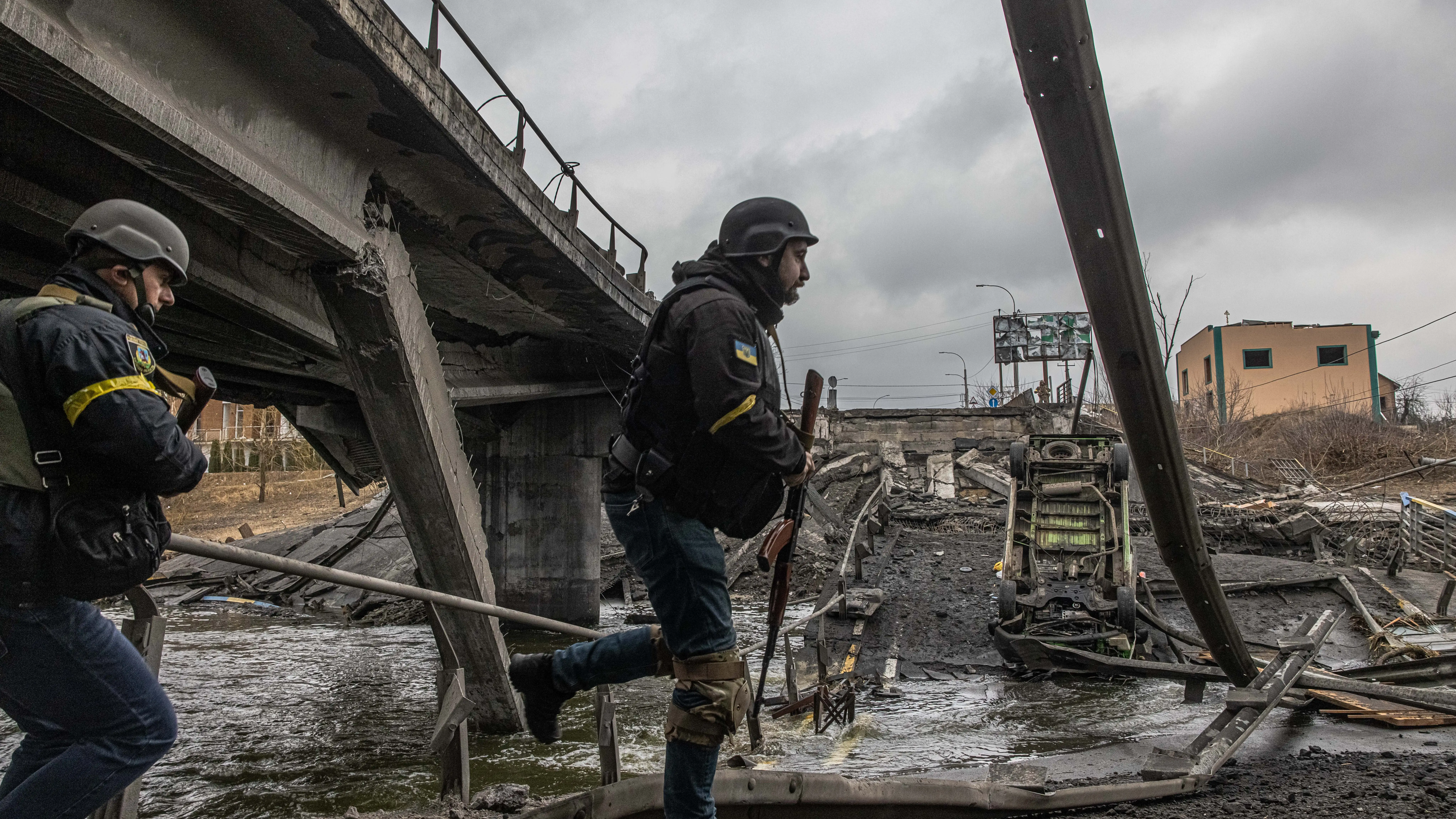 Militares ucranianos pasan junto a un puente destruido Militares ucranianos pasan junto a un puente destruido