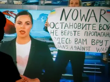 Una mujer ve una transmisión grabada del programa de televisión de noticias del canal ruso Channel One en el que un empleado entró en el estudio con un cartel que se podía leer &quot;No a la guerra&quot;. Detengan la guerra. No creas en la propaganda. Aquí te están mintiendo