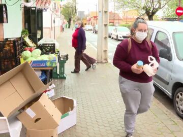 Consumidores en las calles de España, con una frutería al lado
