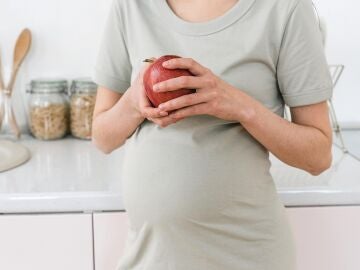 Mujer embarazada sujetando una manzana