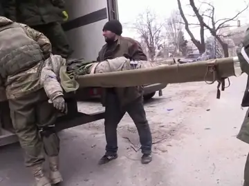 Soldados llevan un cadáver en la invasión rusa de Ucrania