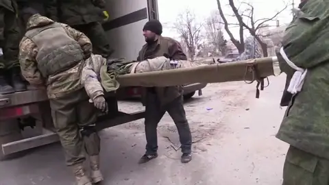 Soldados llevan un cadáver en la invasión rusa de Ucrania Soldados llevan un cadáver en la invasión rusa de Ucrania