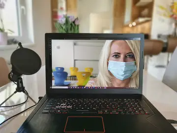 Una mujer con mascarilla a través del ordenador