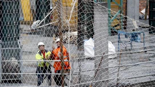 Dos trabajadores de la construcción ajustan una red de seguridad Dos trabajadores de la construcción ajustan una red de seguridad