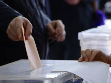 Una persona deposita su voto en la urna de una mesa electoral