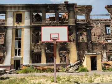 Una canasta de baloncesto frente a una escuela destruida