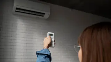 Una mujer encendiendo un aire acondicionado Una mujer encendiendo un aire acondicionado