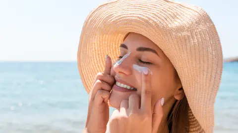 Mujer poniéndose protector solar en la cara Mujer poniéndose protector solar en la cara