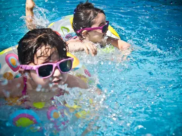 Unas niñas en la piscina con flotadores. Unas niñas en la piscina con flotadores.