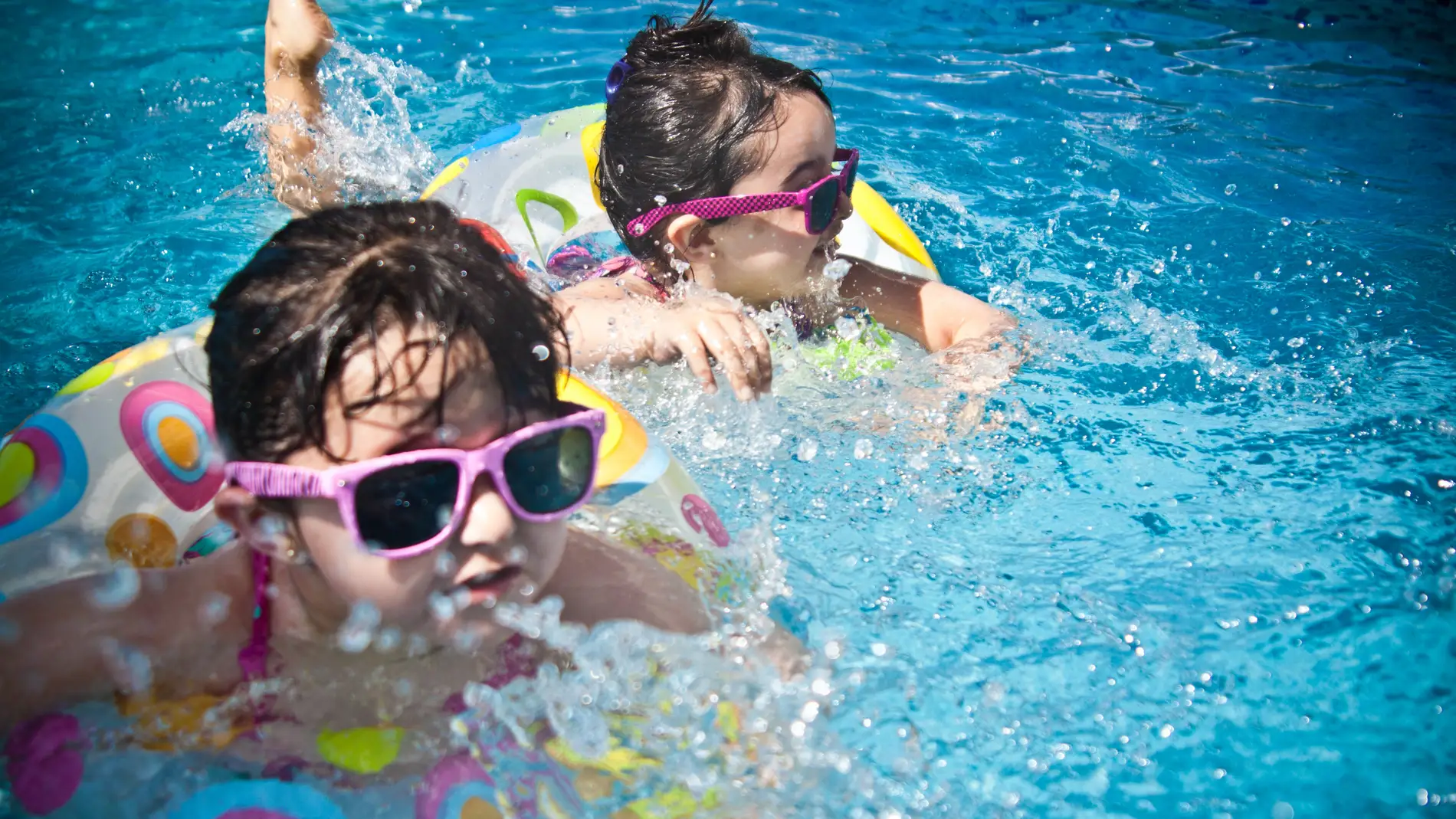Unas niñas en la piscina con flotadores.
