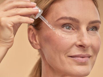 Mujer aplicándose unas gotas de sérum en el rostro