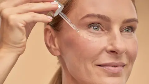 Mujer aplicándose unas gotas de sérum en el rostro Mujer aplicándose unas gotas de sérum en el rostro