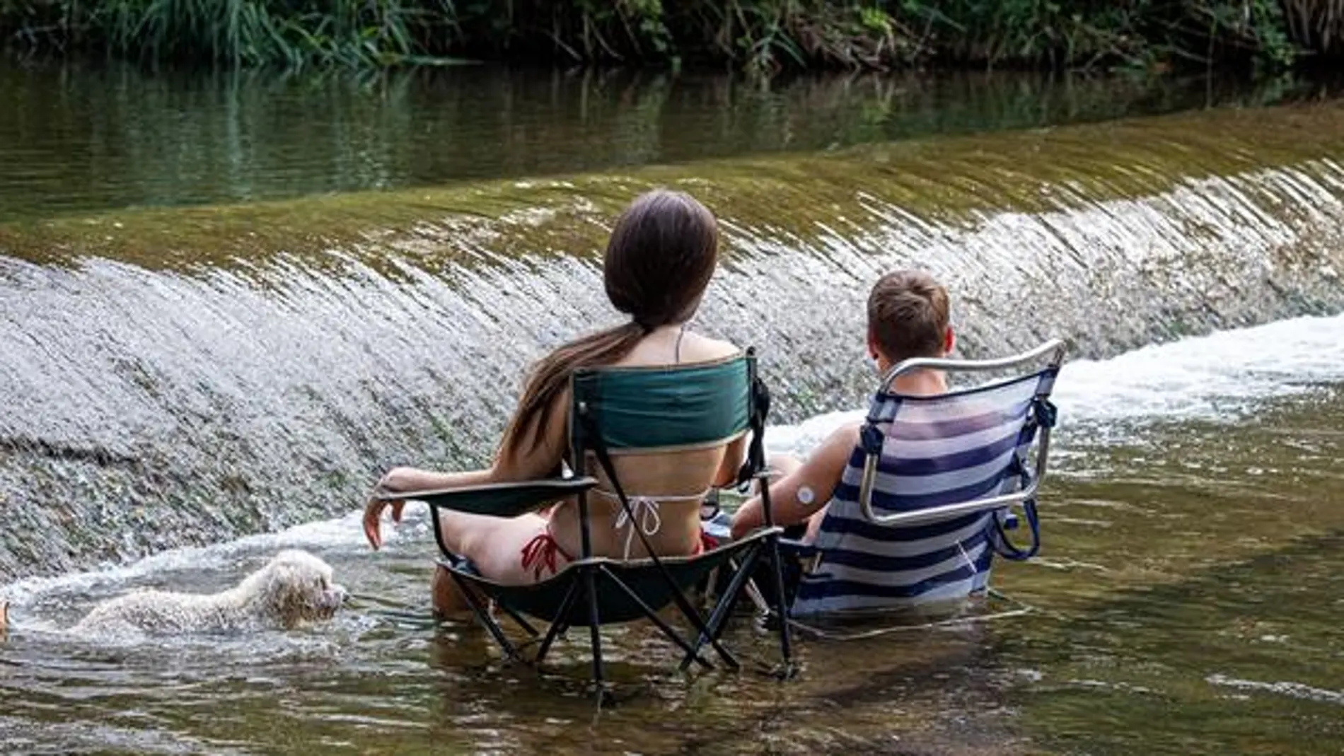 Dos jóvenes se refrescan en un río