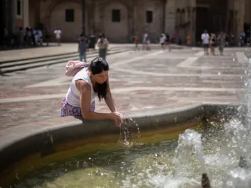 Una mujer se refresca en una fuente. Una mujer se refresca en una fuente.