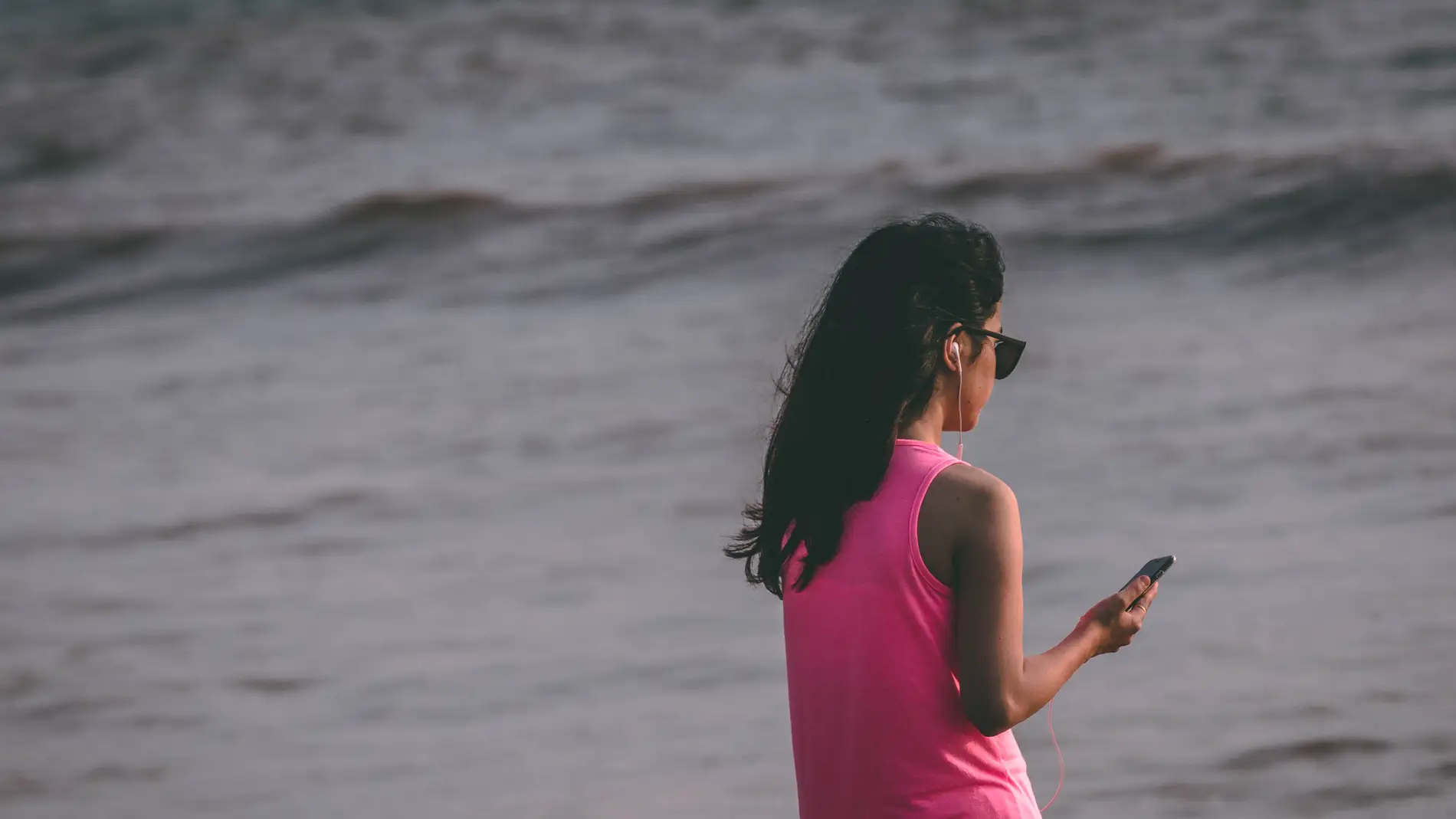 Una mujer mira el móvil en la playa.