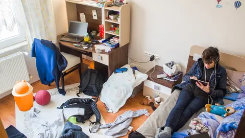 Un adolescente en su desordenada habitación.