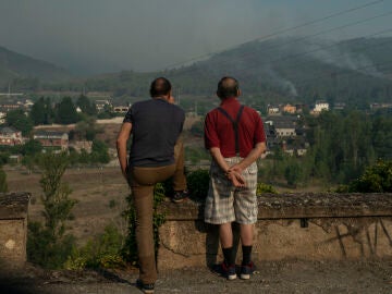 Dos personas observan el incendio forestal cercano a la localidad de Quereño