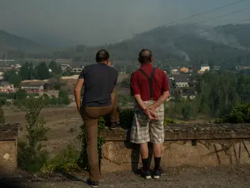 Dos personas observan el incendio forestal cercano a la localidad de Quereño