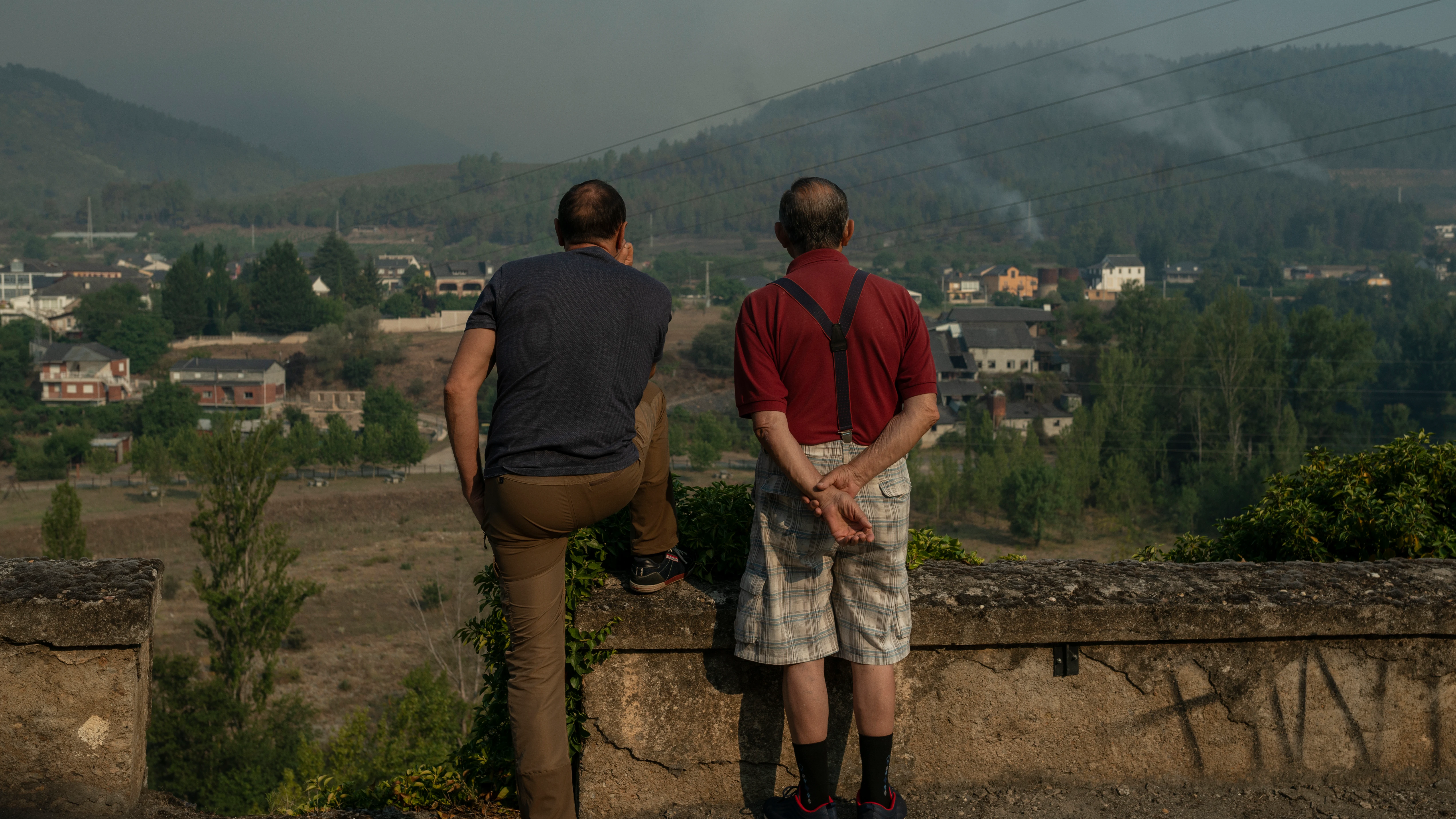 Dos personas observan el incendio forestal cercano a la localidad de Quere&ntilde;o