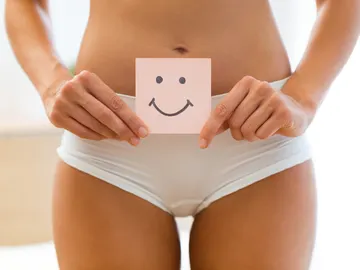 Plano medio del tren inferior de una mujer en bragas con una nota de una cara sonriente Plano medio del tren inferior de una mujer en bragas con una nota de una cara sonriente