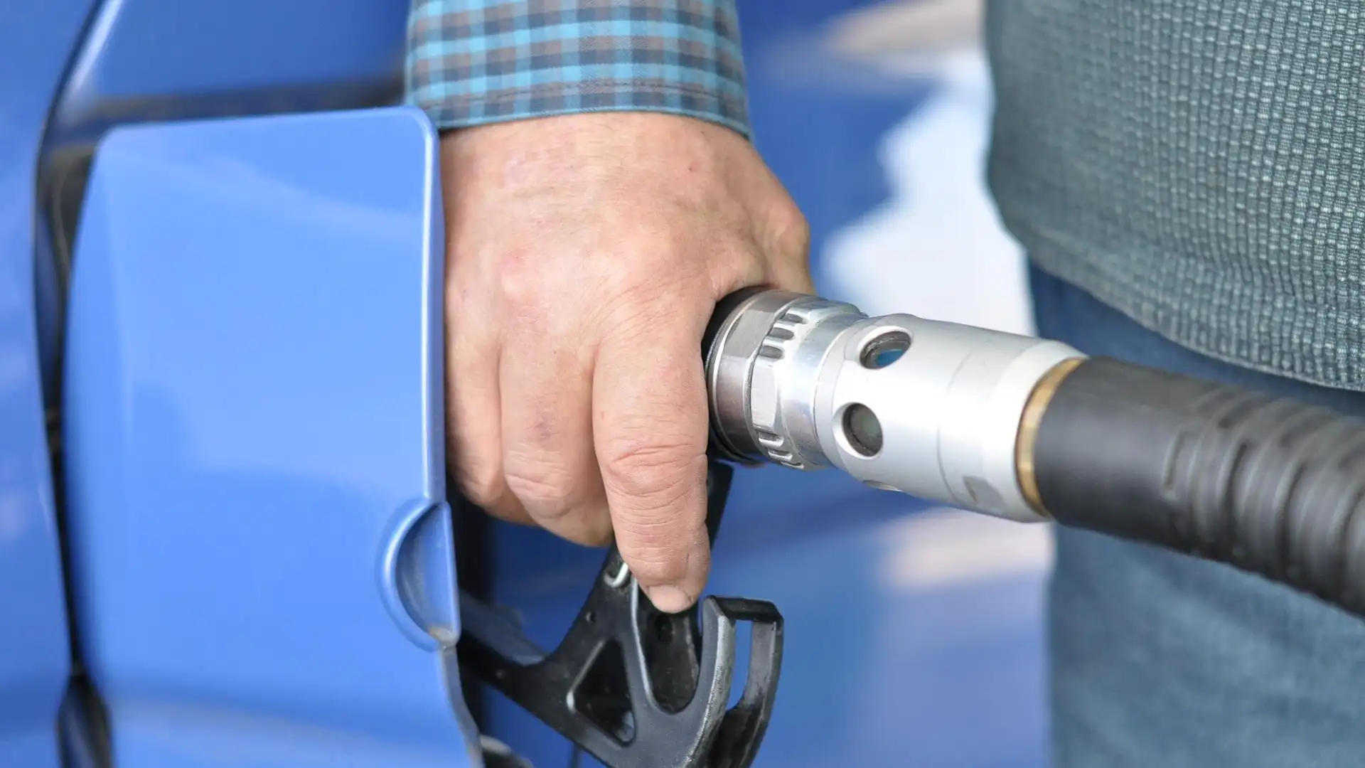 Una persona echando gasolina en su vehículo Una persona echando gasolina en su vehículo